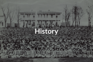 Old image with over a hundred native American children lined up in front of their boarding school with the title History